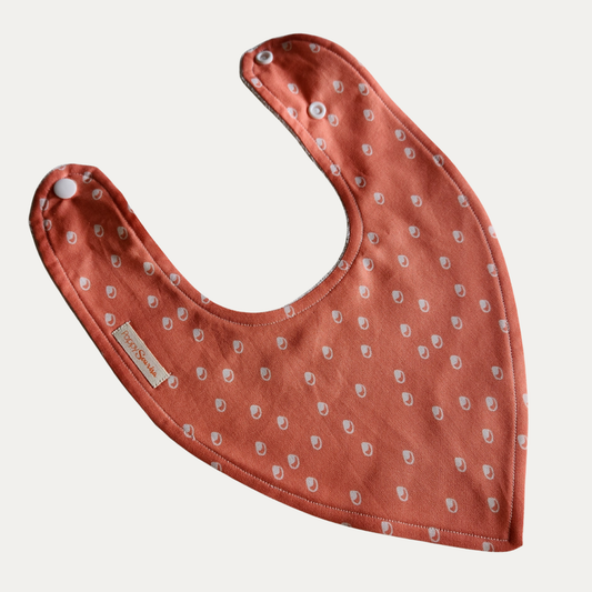 Baby dribble bib with small cream bubble motifs on a tangerine orange background.