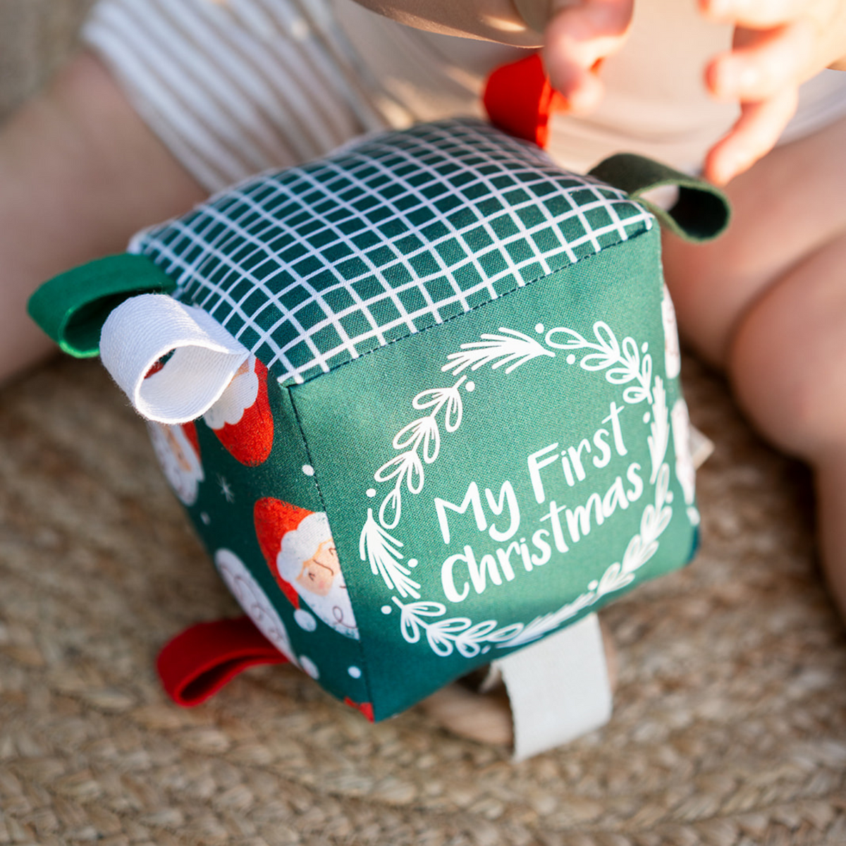 Close-up of the Merry Santa My First Christmas sensory cube showing the Santa print and gingham panel