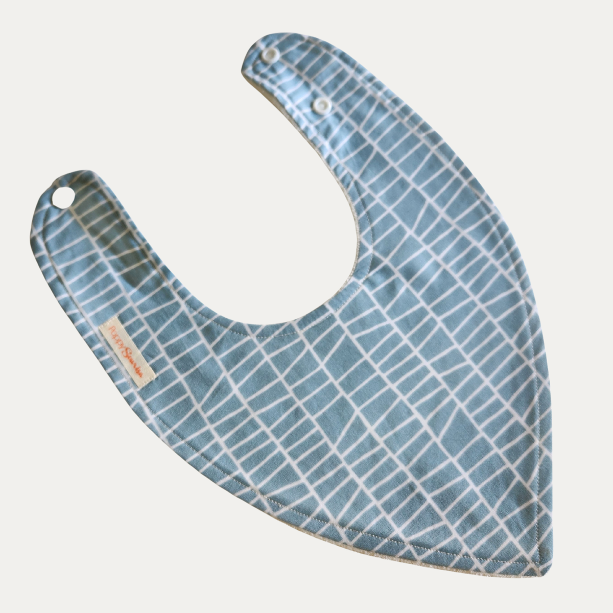 Blue Ladder baby dribble bib featuring white ladder-like lines on a dusty blue background, with adjustable white snaps.