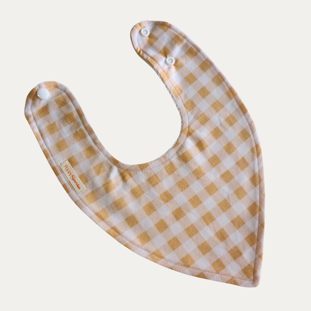 Honey Gingham baby dribble bib featuring mustard yellow, pale pink and white checks with adjustable white snap fasteners.