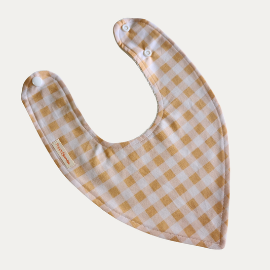 Honey Gingham baby dribble bib featuring mustard yellow, pale pink and white checks with adjustable white snap fasteners.