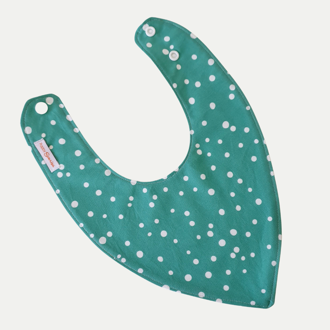 Baby dribble bib with scattered white dots of varying sizes on a green background.