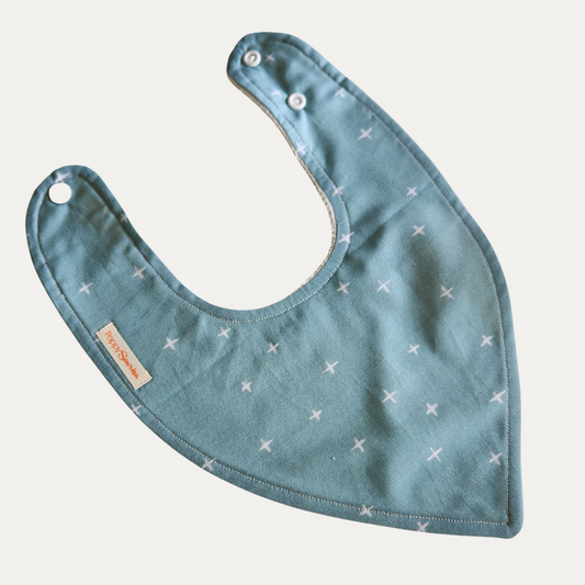 Baby dribble bib with small white crosses on a muted blue-green background.