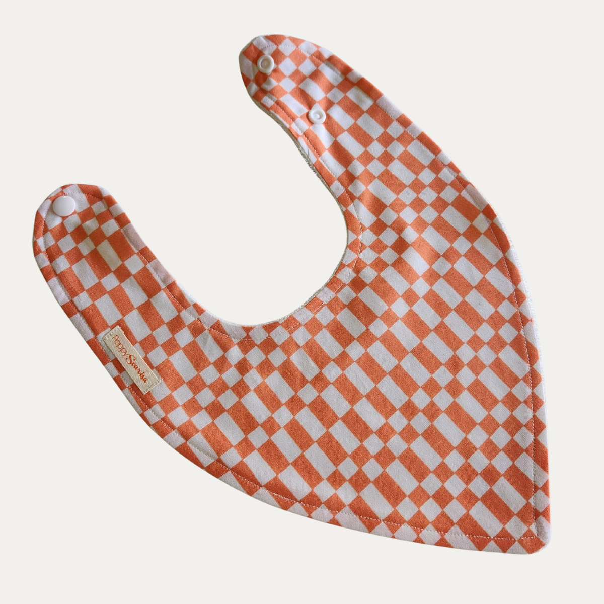 Neo baby dribble bib featuring an orange and white checkerboard pattern with adjustable white snap fasteners.