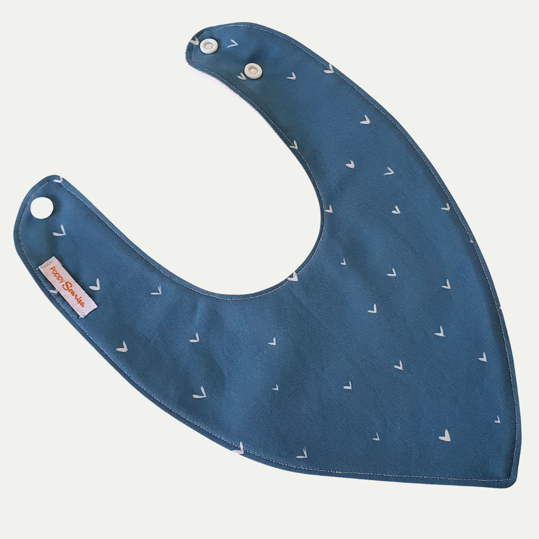 Baby dribble bib with tiny white hand-drawn hearts on a peacock blue background.