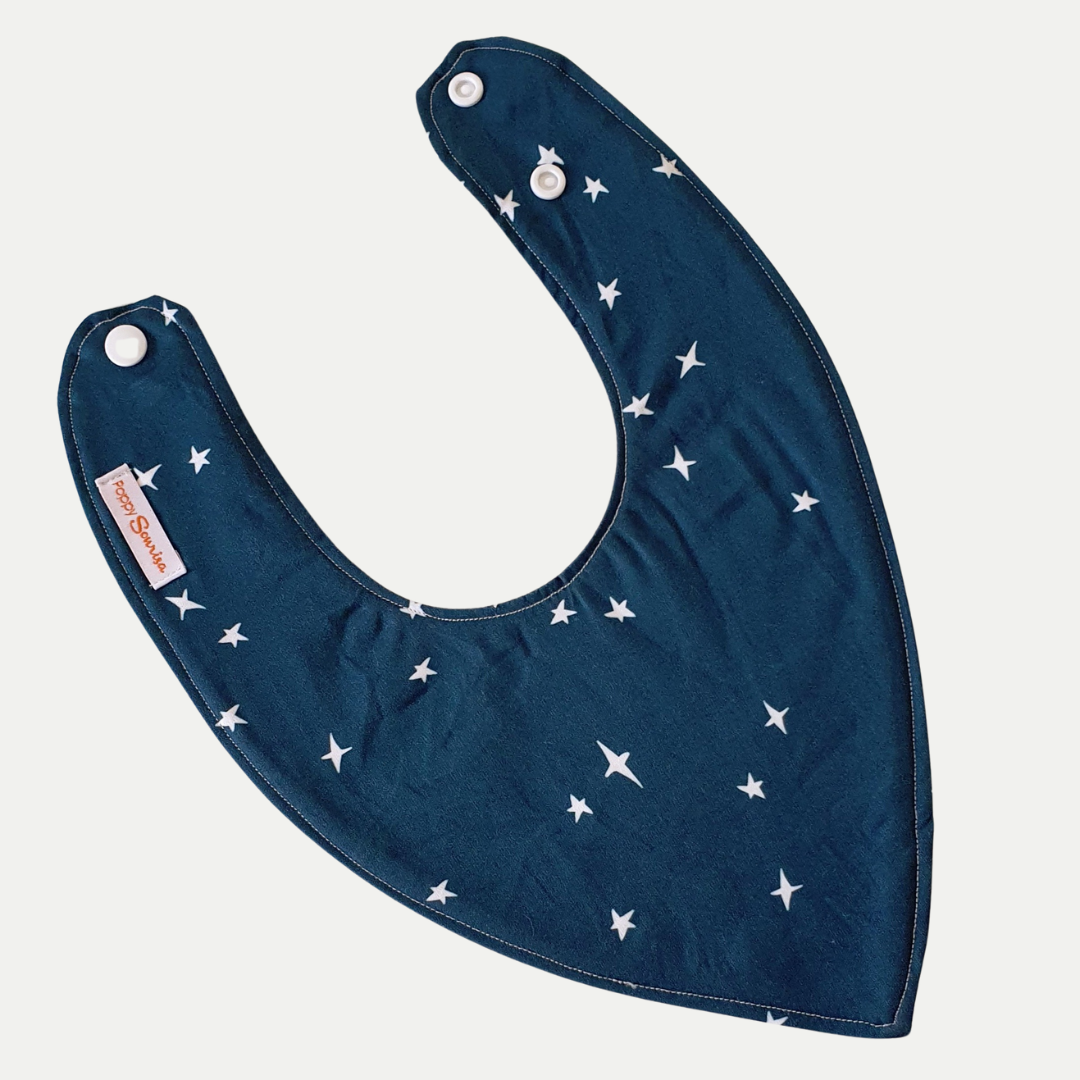 Baby dribble bib with scattered white four-pointed stars on a deep peacock blue background.