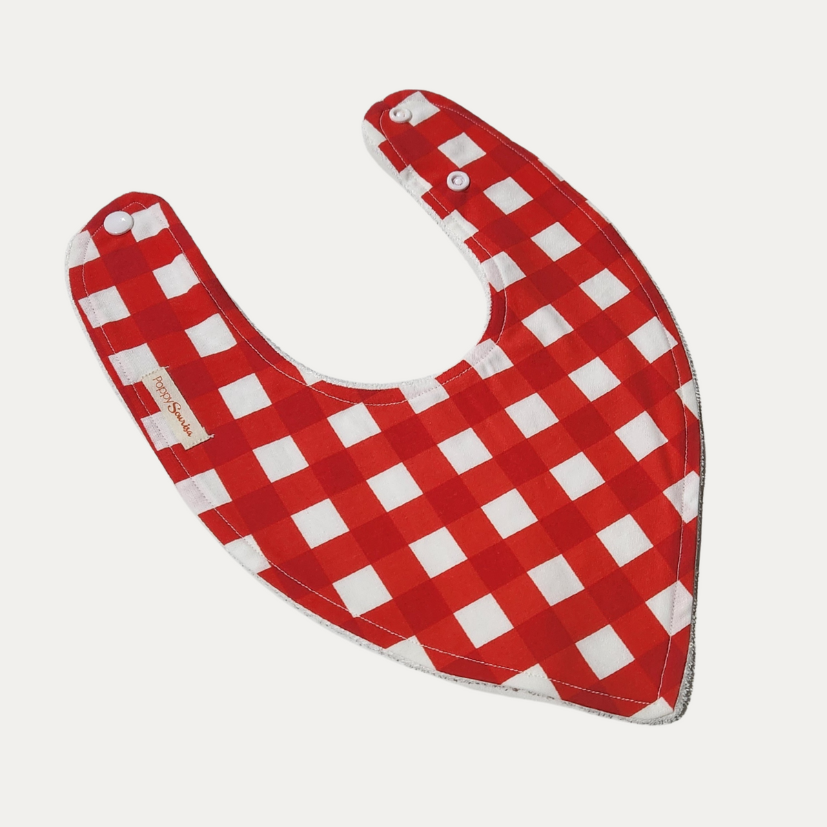 Red Gingham baby dribble bib featuring red and white checks with adjustable white snap fasteners.