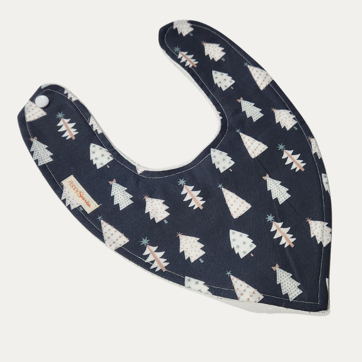Scandi Christmas baby dribble bib featuring stylised cream Christmas trees with pastel details on a navy background.